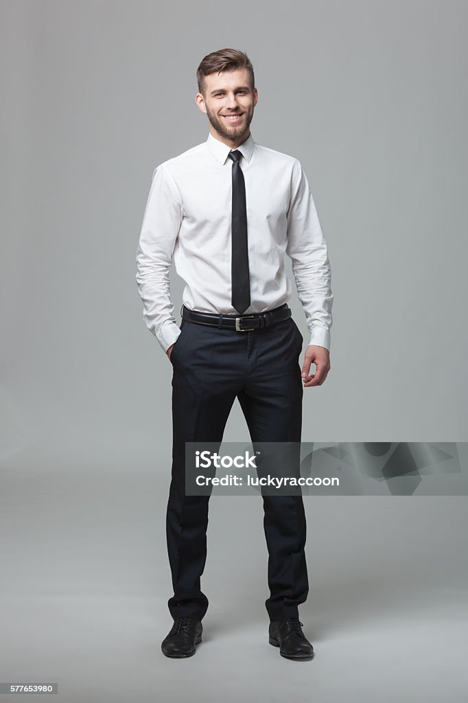 Portrait of handsome young businessman on white background. Portrait of handsome young businessman standing against gray background. Men Stock Photo