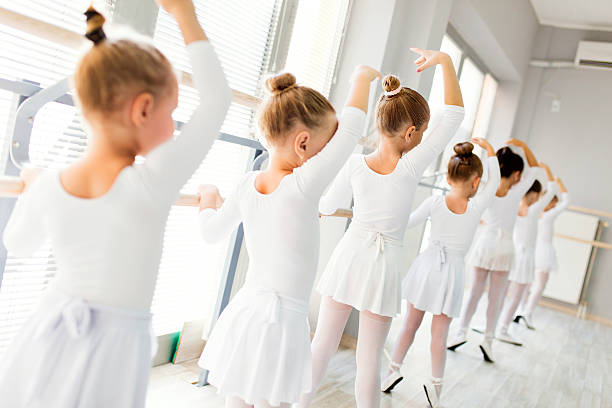 piccole ballerine che usano barre mentre si esercitano in studio di danza. - scuola di danza classica foto e immagini stock