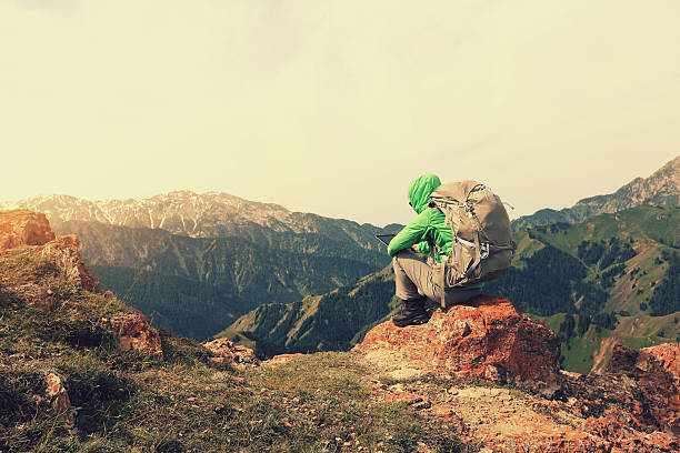 istock woman backpacker use digital tablet  on mountain peak cliff 577654488
