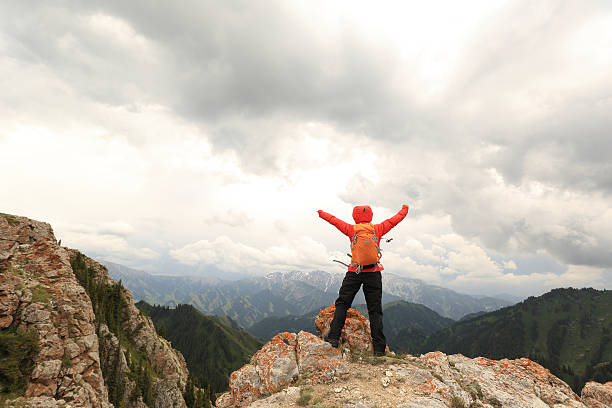 istock cheering successful woman backpacker open arms on mountain peak 577655570