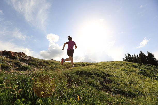 healthy young woman trail runner running on beautiful mountain peak