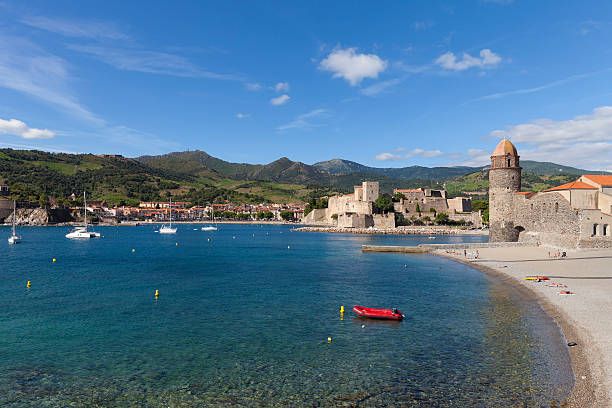 Collioure, France - July 03, 2016. View of the picturesque Collioure, situated in the Département Pyrénées-Orientales. Château Royal in the centre of the picture. The beach is highly frequented by tourists and natives. Pyrenees Mountain Range in the background.
