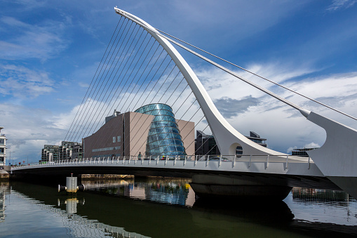 Dublin, Ireland - June 24, 2016: The Samuel Beckett Bridge and the building on the waterfront near the Convention Center - Dublin city center in the republic of Ireland. This is a cable-stayed bridge that joins Sir John Rogerson's Quay on the south side of the River Liffey to Guild Street and North Wall Quay in the Docklands area. The innovative architect Santiago Calatrava designed this and a number of other bridges and buildings in Ireland. The Dublin Convention Centre can also be seen in the background. It was designed by the American-Irish architect Kevin Roche.