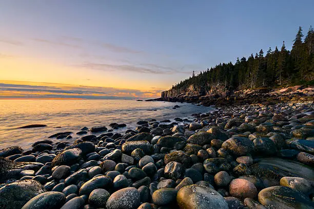 Rocky beach in Acadia National Park, Maine with view of Otter Cliffs at sunrise.
