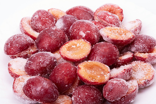 Fresh frozen red plums on a white background