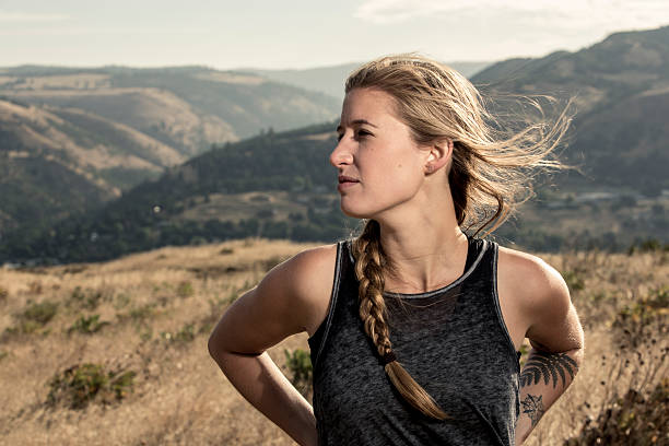 A young athletic woman scanning the horizon of a scenic environment with copy space. She is enjoying a peaceful moment in nature with the wind blowing through her hair (stock image).