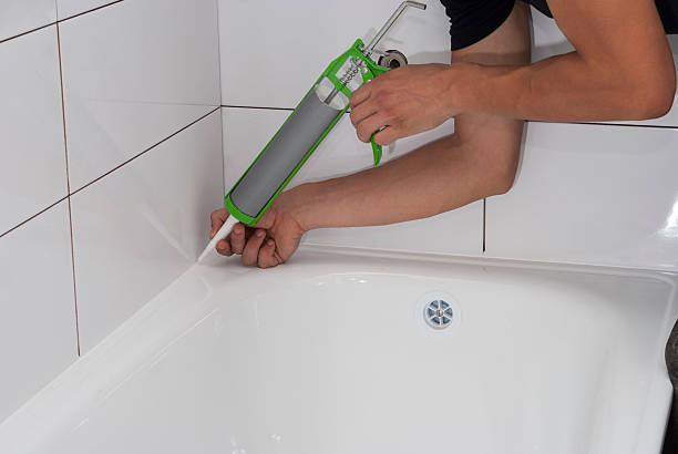 waterproofing bath silicone sealant plumber apply silicone sealant to the joint bathtubs and ceramic tile sealant photos stock pictures, royalty-free photos & images