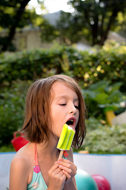 istock Caucasian girl eating popcicle in pool 577935812