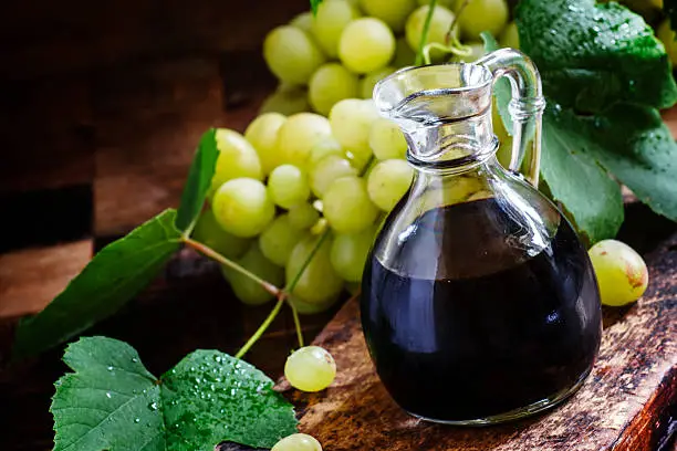 Balsamic vinegar in a glass jug, vintage wooden background, rustic style, selective focus