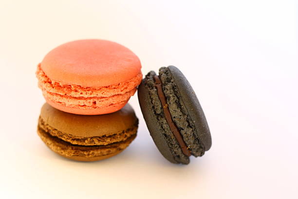 Three french macarons in pink, black, brown color on white stock photo