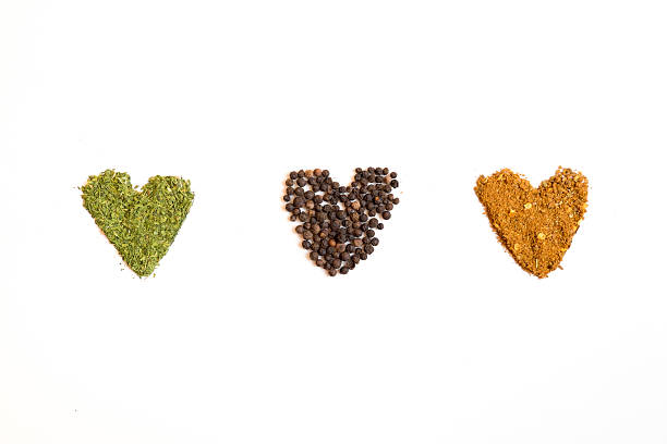 Three hearts made of spices and dry herbs of different types and colors on the white background with copy space