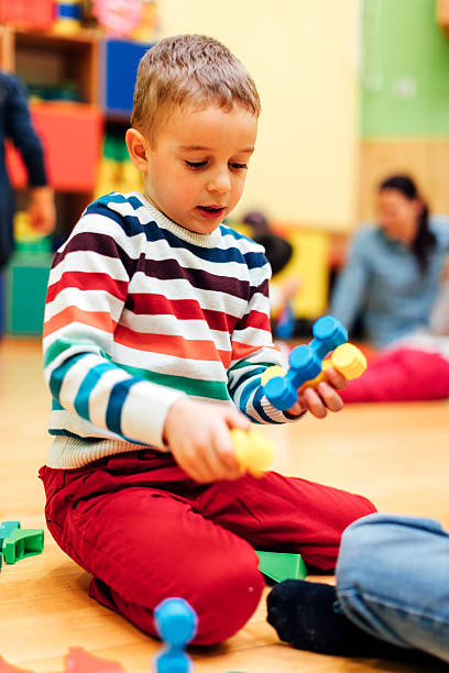 istock Cute boy in kindergarten playing with colorful blocks 577939736