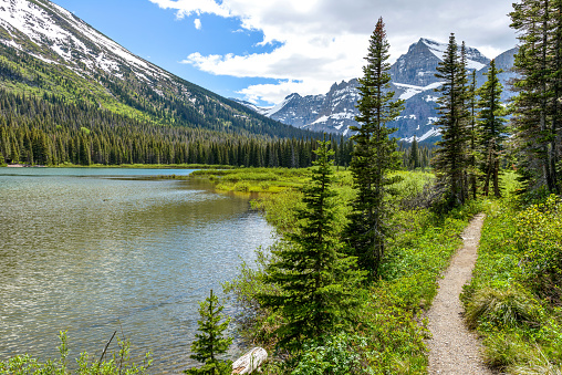 A spring view of a hiking trail along Lake Josephine at the base of Mount Gould in Many Glacier region of Glacier National Park, Montana, USA.