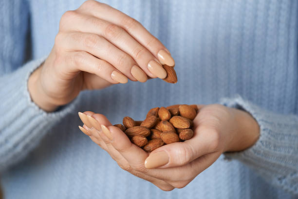 Close Up Of Woman Holding Handful Of Almonds stock photo