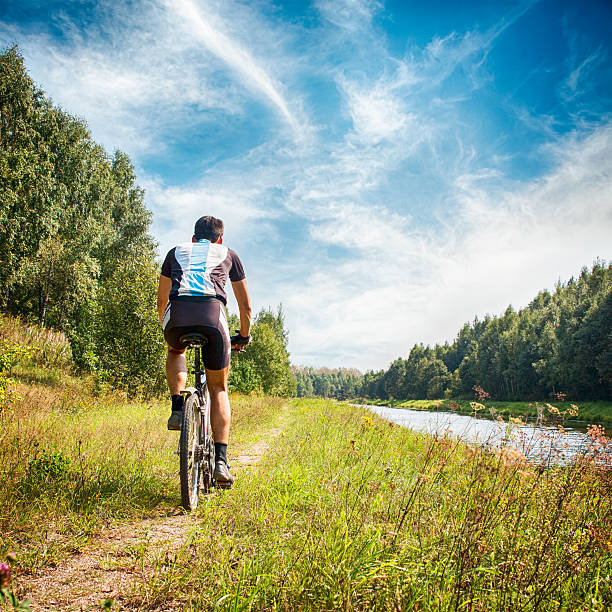 istock Man Riding a Bicycle on River Bank. Summer Photo. 577948818
