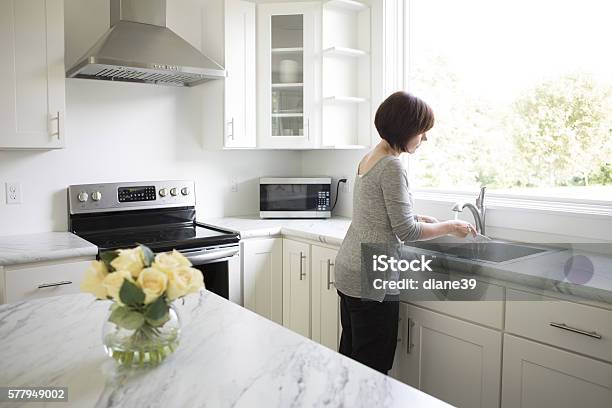 Woman Working In A Modern Kitchen Stock Photo - Download Image Now - Cleaning, Kitchen Hood, Kitchen Island