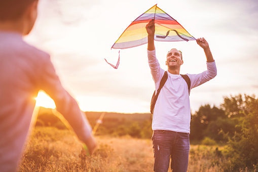 Four little kids running in the park with kite happy and smiling