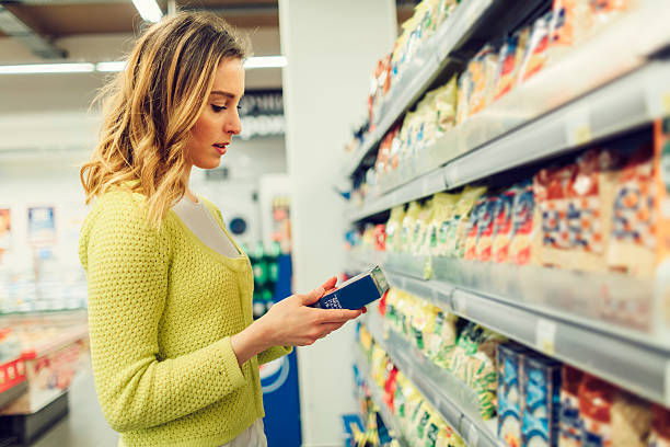 若い女性食料品ショッピング、地元のスーパー。 - 栄養成分表示 ストックフォトと画像