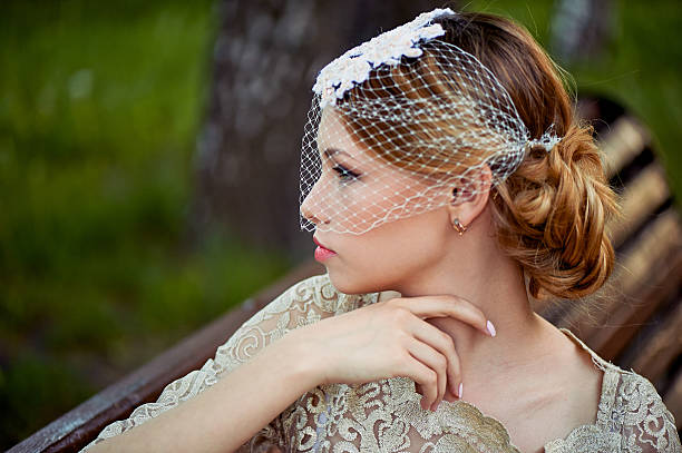 istock Beautiful blonde with a hairstyle and veil sitting on bench 577951470