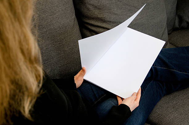 istock Woman is opening white blank brochure with copy space 577954074