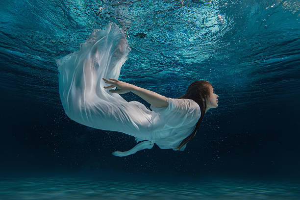 istock Woman in a white dress under water. 577954756
