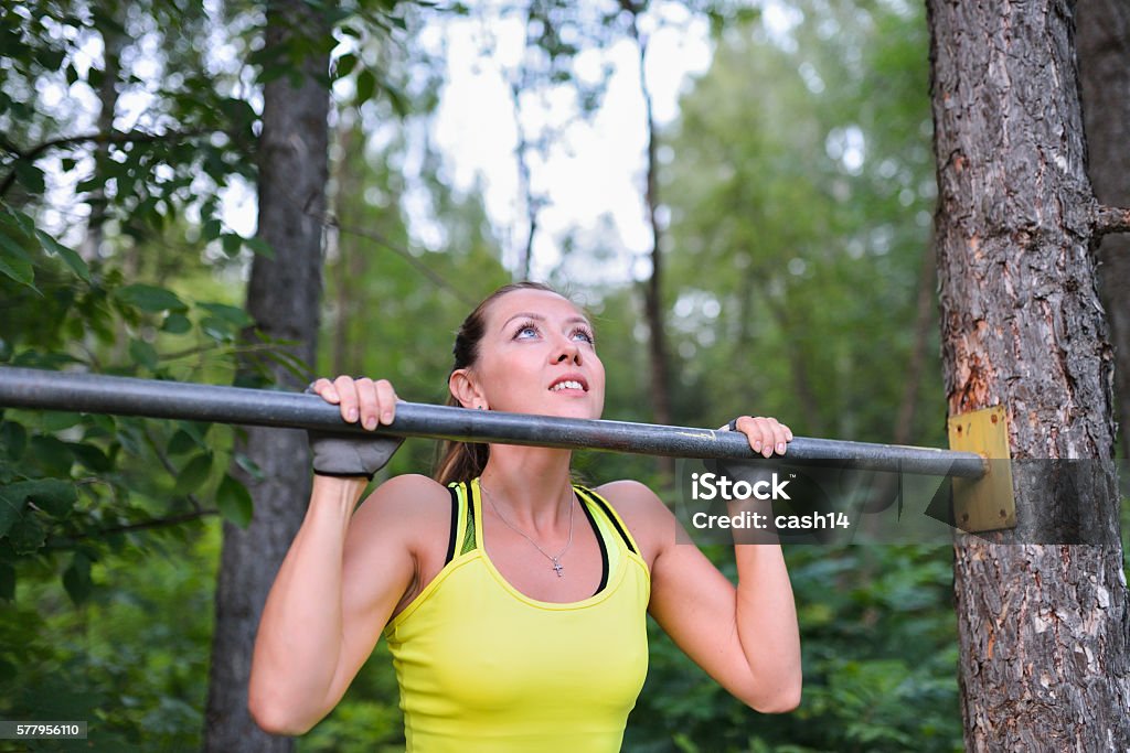 Fit woman training pull ups on horizontal bar in city Fit woman training pull ups on horizontal bar in city park outdoors. Active Lifestyle Stock Photo