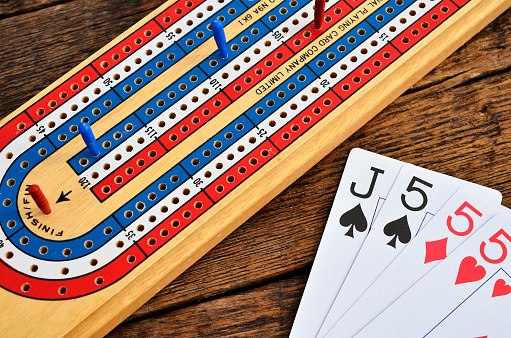 A close up image of a colourful cribbage board with playing cards.