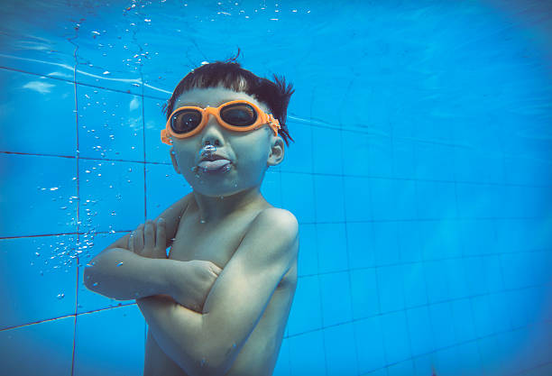 A little girl swimming under water blowing bubbles.