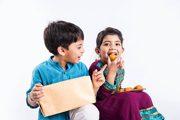 indian small brother and sister having fun on rakshabandhan indian small brother and sister enjoying and celebrating Raksha Bandhan festival india sweets stock pictures, royalty-free photos & images