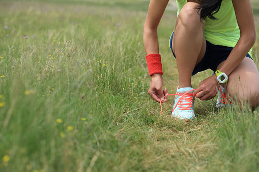 young fitness woman runner tying shoelace on nature trail