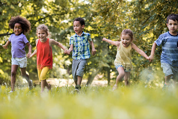 istock Playful kids holding hands and running in the park. 577971940