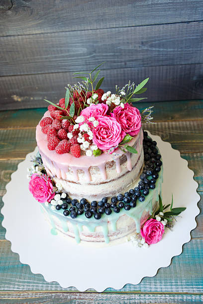 istock wedding color drip cake with roses, blueberries and  raspberries 577972392
