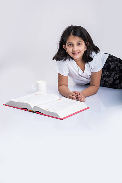 istock indian small girl child reading book on ground 577976182