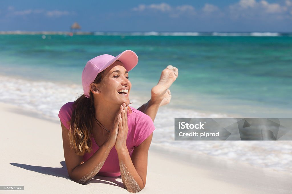 portrait of a woman smiling on the sand portrait of a beautiful smiling woman lying on her stomach on the sand by a heavenly sea 30-34 Years Stock Photo