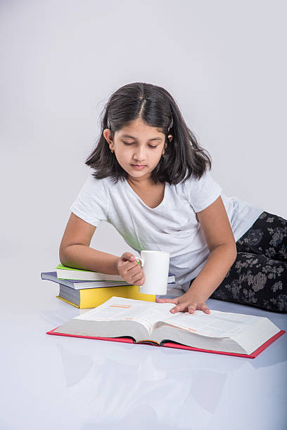 istock indian small girl child reading book on ground 577976506