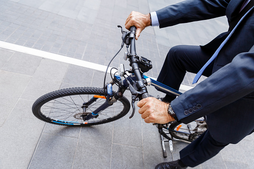 Successful businessman in suit riding bicycle 