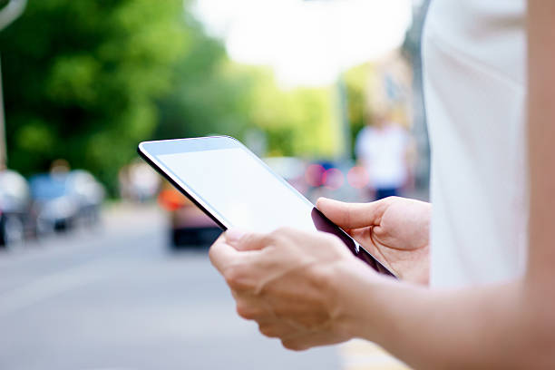 istock Closeup of hand holding tablet on street background 577978162