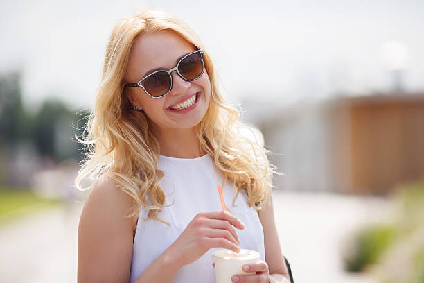 istock Smiling blonde drinking milkshake or smoothies in summer day 578076246