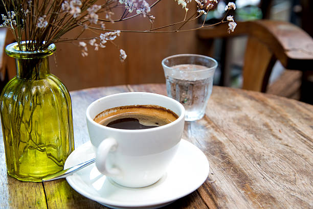 istock White coffee cup with dry flower on wooden table. 578077944