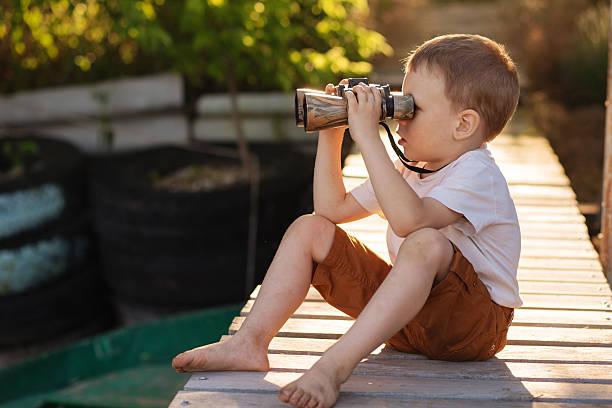 istock Little boy looking through binoculars on river bank 578079666