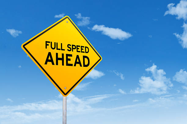 Image of a yellow signboard with text of Full Speed Ahead under clear sky