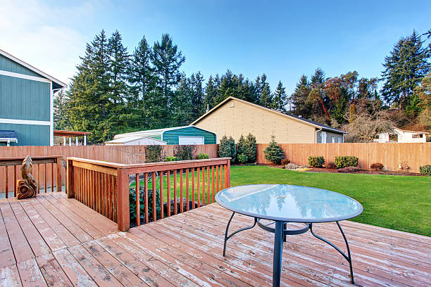 istock Walkout deck with table. Fenced backyard with well kept lawn 578081896