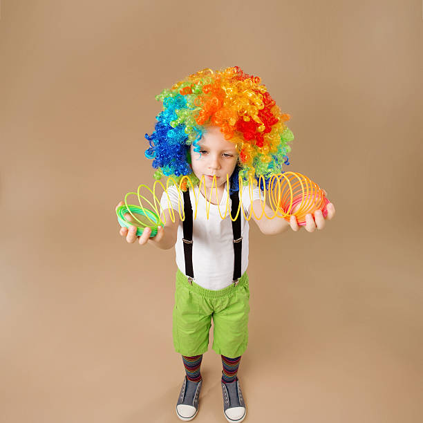 istock Little boy in clown wig plays with a spring. 578081916