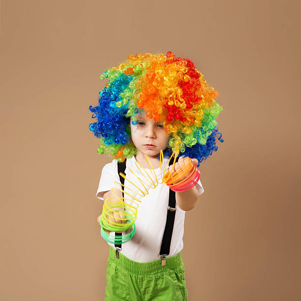 istock Little boy in clown wig playing with a spring. 578082064