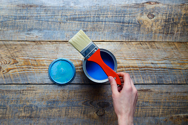istock open can blue paint with hand on wooden background 578082302