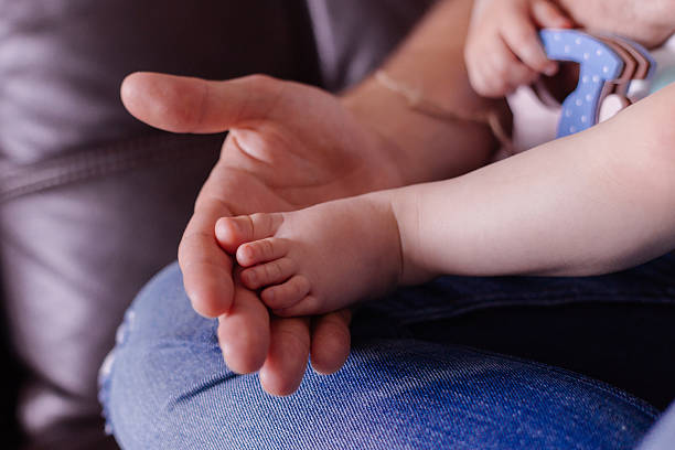 istock Man hold baby leg in hand 578082406