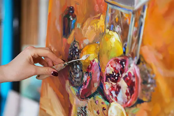 Woman hand painting in yellow with spatula. artist paints a picture of oil paint with palette-knife closeup