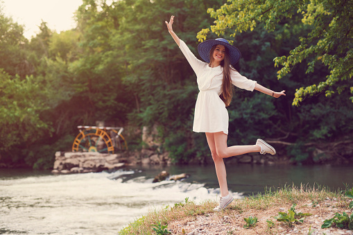 Carefree young woman enjoying a beautiful summer day in nature by the river.