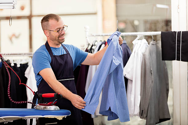 Dry Cleaners Young dry cleaner working in shop. iron laundry cleaning ironing board stock pictures, royalty-free photos & images