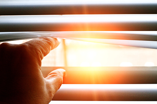 Mann looking through a jalousie on a sunny day